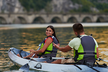 Image showing A young couple enjoying an idyllic kayak ride in the middle of a beautiful river surrounded by forest greenery