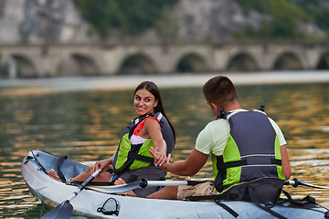 Image showing A young couple enjoying an idyllic kayak ride in the middle of a beautiful river surrounded by forest greenery