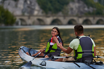 Image showing A young couple enjoying an idyllic kayak ride in the middle of a beautiful river surrounded by forest greenery