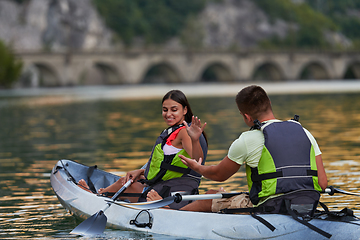 Image showing A young couple enjoying an idyllic kayak ride in the middle of a beautiful river surrounded by forest greenery