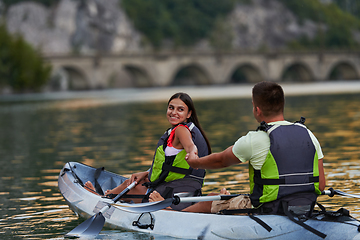 Image showing A young couple enjoying an idyllic kayak ride in the middle of a beautiful river surrounded by forest greenery