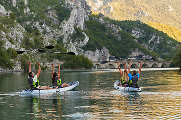 Image showing A group of friends enjoying having fun and kayaking while exploring the calm river, surrounding forest and large natural river canyons