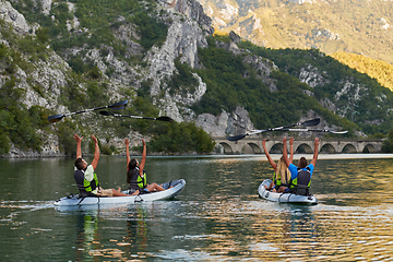 Image showing A group of friends enjoying having fun and kayaking while exploring the calm river, surrounding forest and large natural river canyons