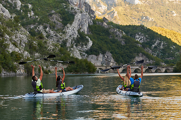 Image showing A group of friends enjoying having fun and kayaking while exploring the calm river, surrounding forest and large natural river canyons