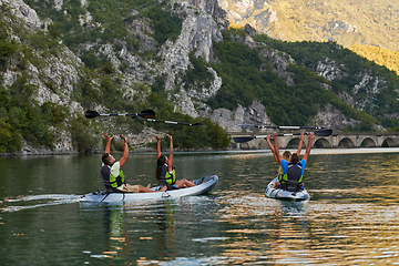 Image showing A group of friends enjoying having fun and kayaking while exploring the calm river, surrounding forest and large natural river canyons