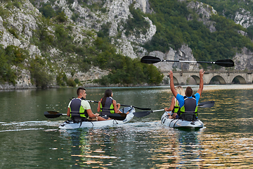 Image showing A group of friends enjoying having fun and kayaking while exploring the calm river, surrounding forest and large natural river canyons