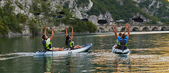 Image showing A group of friends enjoying having fun and kayaking while exploring the calm river, surrounding forest and large natural river canyons