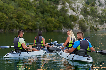 Image showing A group of friends enjoying having fun and kayaking while exploring the calm river, surrounding forest and large natural river canyons