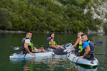 Image showing A group of friends enjoying having fun and kayaking while exploring the calm river, surrounding forest and large natural river canyons