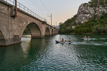 Image showing A group of friends enjoying having fun and kayaking while exploring the calm river, surrounding forest and large natural river canyons