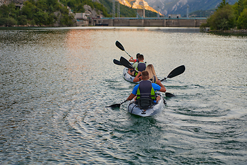 Image showing A group of friends enjoying having fun and kayaking while exploring the calm river, surrounding forest and large natural river canyons