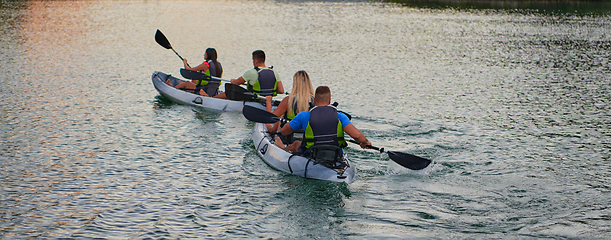 Image showing A group of friends enjoying having fun and kayaking while exploring the calm river, surrounding forest and large natural river canyons