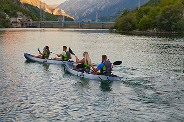 Image showing A group of friends enjoying having fun and kayaking while exploring the calm river, surrounding forest and large natural river canyons