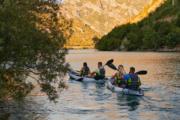 Image showing A group of friends enjoying having fun and kayaking while exploring the calm river, surrounding forest and large natural river canyons