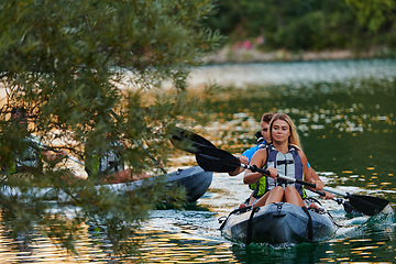 Image showing A group of friends enjoying having fun and kayaking while exploring the calm river, surrounding forest and large natural river canyons