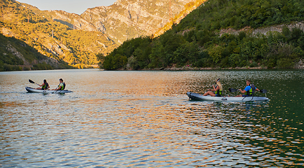 Image showing A group of friends enjoying having fun and kayaking while exploring the calm river, surrounding forest and large natural river canyons