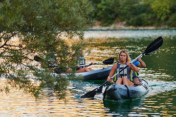 Image showing A group of friends enjoying having fun and kayaking while exploring the calm river, surrounding forest and large natural river canyons