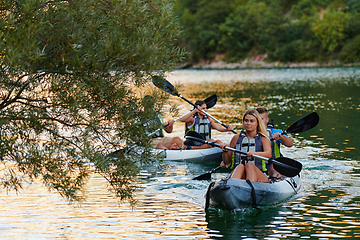 Image showing A group of friends enjoying having fun and kayaking while exploring the calm river, surrounding forest and large natural river canyons