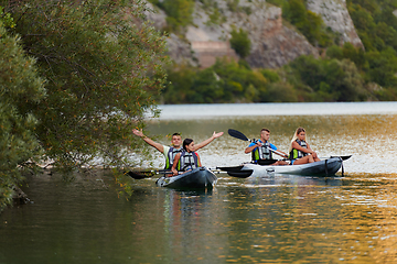 Image showing A group of friends enjoying having fun and kayaking while exploring the calm river, surrounding forest and large natural river canyons