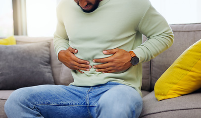 Image showing Man on a sofa with stomach pain, sickness or cramps while relaxing in the living room at his home. Medical emergency, illness and male with diarrhea, indigestion or food poisoning ache at his house.