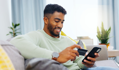 Image showing Credit card, finance and man with smartphone for online shopping in lounge at home. Indian, visa and money for e commerce transaction and search the internet for investment or product.