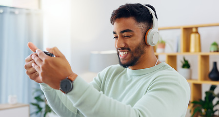 Image showing Indian man with smartphone, headphones and face, music and smile, scroll social media and audio streaming. Online, listening to radio or podcast with happiness and relax with texting or email