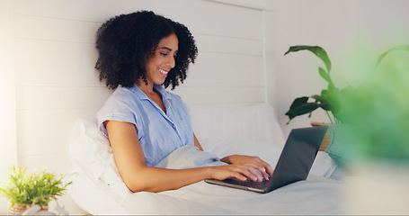 Image showing Blog writer typing with laptop for internet streaming website and reading funny social media post in bed at home. Woman freelance worker in bedroom working remote while writing funny or comic web con