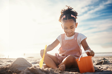 Image showing Sand, castle and girl kid at beach for fun games, freedom and summer holiday with mockup sky. Happy child, bucket and building with play toys at sea for development, vacation and relax in sunshine