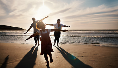 Image showing Family, running and freedom on beach with sunset, shadow and fun together, games and bonding on vacation. Travel, adventure and playful, parents and child with happy people in nature and energy