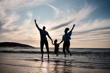 Image showing Family, jump and freedom on beach with silhouette, fun together outdoor with games and bonding on vacation. Travel, adventure and playful, parents and child with happy people in air and energy