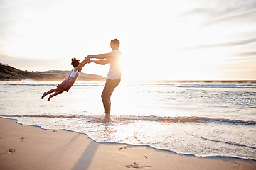 Image showing Beach, swing and father with girl child holding hands in nature for play, freedom or bond at sunset. Ocean, travel and parent with kid at sea for spinning fun, games and celebration adventure in Bali