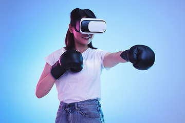 Image showing AI, virtual reality and a gamer woman boxing on a blue background in studio for fitness or exercise. Metaverse, sports and training with a young female boxer playing an online fantasy game for health