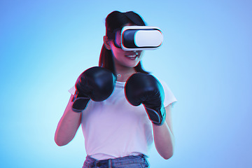 Image showing Virtual reality, metaverse and a gamer woman boxing on a blue background in studio for fitness or exercise. AI, sports and training with a young female boxer playing an online fantasy game for health