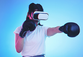 Image showing AI, metaverse and a gamer woman boxing on a blue background in studio for fitness or exercise. Virtual reality, sports and training with a young female boxer playing an online fantasy game for health
