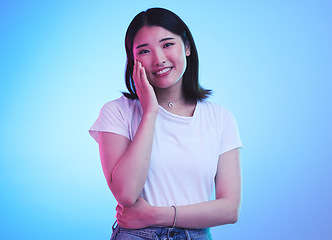 Image showing Face, smile and Asian woman with beauty or dream with hope or happiness isolated in a studio blue background. Cute, shy and happy young female person with skincare or soft skin and with a memory