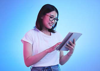 Image showing Young woman, student and tablet for online education, e learning and study on blue, studio background. Happy person typing on digital technology, reading social media and school or youth information