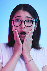 Image showing Surprise, shocked and face of Asian woman with wow expression or open mouth for drama, deal and promotion. Omg, wtf and portrait of person with discount emoji isolated in a studio blue background