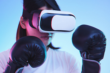 Image showing Sports, metaverse and a gamer woman boxing on a blue background in studio for fitness or exercise. Virtual reality, ai and training with a young female boxer playing an online fantasy game for health