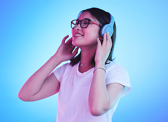 Image showing Young woman, student and headphones for listening, audio streaming and happy subscription on blue background. Gen z, youth or person smile for mental health music or podcast on electronics in studio