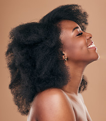 Image showing Beauty, hair and profile with a natural black woman in studio on a brown background for organic cosmetics. Face, smile and haircare with a happy young afro female person indoor for shampoo treatment