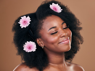 Image showing Hair care, flowers and black woman, happy and beauty in studio isolated on a brown background. Smile, floral afro cosmetics or natural African model in organic salon treatment, wellness and hairstyle