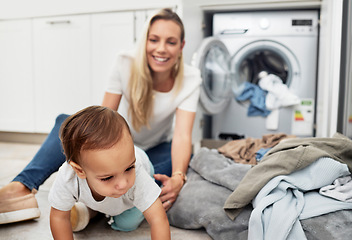 Image showing Child, mother and laundry at home with family for housework, chores and clean clothes. A happy woman with a washing machine for cleaning and playing with toddler kid while multitasking as a mom