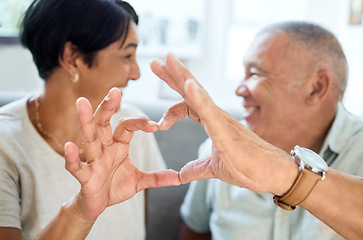 Image showing Heart shape, hands and senior couple bonding and talking in the living room of their home. Happy, smile and closeup of an elderly man and woman in retirement with a love sign or gesture together.