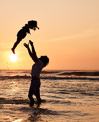 Image showing Father, throw and child in air at beach, sunset and waves in the ocean for happiness, fun and support on adventure. Parent, kid and silhouette of dad in the sea with love to play a game with girl