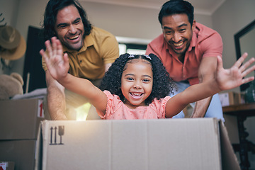 Image showing Family home, girl and box with dad, push and gay parents with games, portrait and excited on floor with moving. LGBTQ men, female child and cardboard package for car, airplane and speed in new house