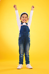Image showing Portrait, children and a winner girl on a yellow background in celebration of success or victory. Kids, goals and motivation with a young child cheering for an award or achievement in studio