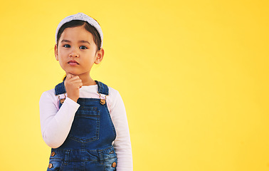 Image showing Girl child, studio portrait and space for thinking, promotion or mockup by yellow background. Young female kid, fashion and trendy clothes with hand by face for idea, style or confused with memory