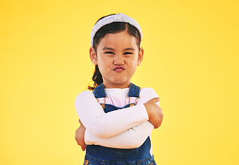 Image showing Portrait, arms crossed and angry girl child in studio with bad, attitude or behavior problem on yellow background. Frown, face and asian kid with body language for no, frustrated or tantrum emoji