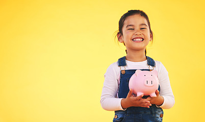 Image showing Girl child, piggy bank and saving in studio portrait with smile, mockup space and excited by yellow background. Young female kid, money box and start investment for promo, financial knowledge or goal