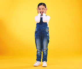 Image showing Excited, happy and hands on face of girl child in studio with news, sale or fashion giveaway on yellow background. Wow, emoji and kid winner with celebration gesture for coming soon surprise prize